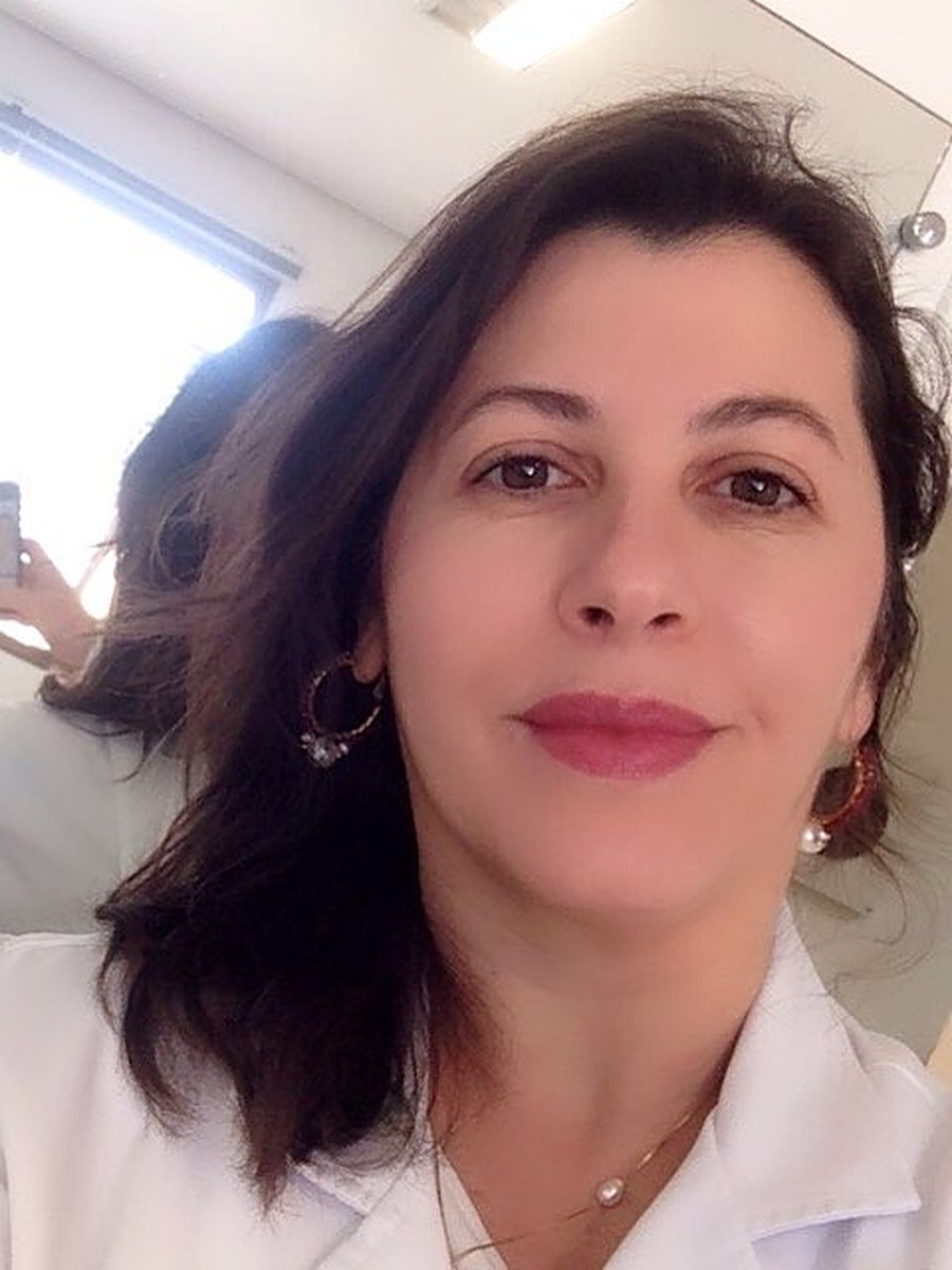 Dra. Angélica Climachauska de jaleco branco no consultório
